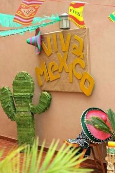 a sign that says viva mexico next to a cactus and sombrero with decorations on it