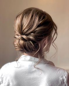 a woman with her hair in a low bun, looking off to the side and wearing a white shirt