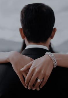 a bride and groom hold hands as they look at each other with their wedding rings