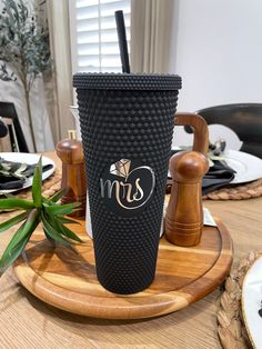 a black coffee cup sitting on top of a wooden tray