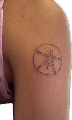 a small sand dollar tattoo on the back of a woman's left upper arm