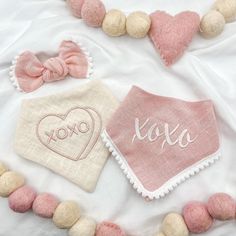 two pink and white heart shaped items on a bed with pom - poms