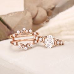 two rose gold rings with white diamonds on top and one in the middle, sitting next to each other