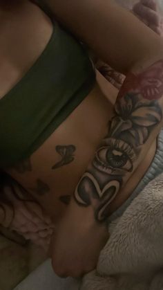 a woman laying on top of a bed with tattoos on her stomach and hand behind her back