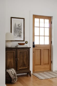 a wooden door in a white room with a rug on the floor next to it