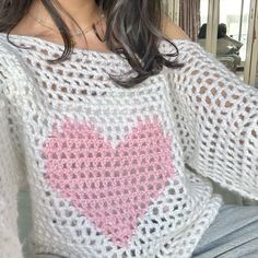 a woman wearing a white sweater with a pink heart on it