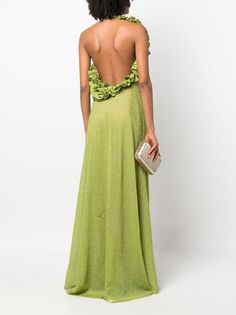 the back of a woman wearing a green dress with ruffles and a clutch