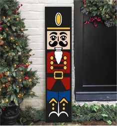 a christmas door hanger with a nutcracker on it next to a tree