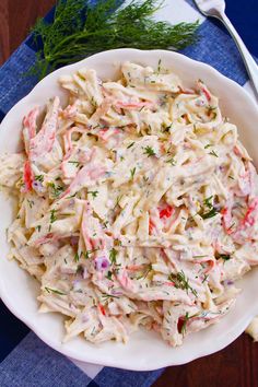 a white bowl filled with pasta salad on top of a blue table cloth