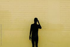 a man standing in front of a yellow wall talking on a cell phone