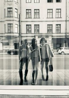 three women are standing in front of a window