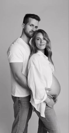 a man and woman pose for a black and white photo while holding their pregnant belly