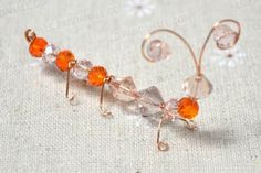 an orange beaded wire is attached to the side of a piece of glass beads