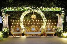 an outdoor wedding setup with white flowers and candles on the stage, surrounded by greenery