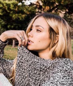 a woman with blonde hair wearing a black and white sweater is posing for a photo