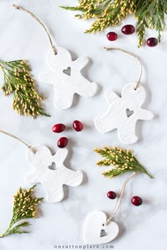 christmas ornaments made out of white wooden pieces and greenery on a marble surface with red berries