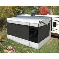 a trailer with a tent attached to it in the grass next to trees and leaves