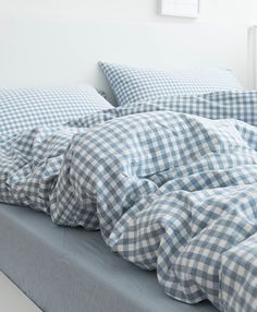 an unmade bed with blue and white checkered sheets