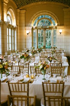 the tables are set up with white linens and floral centerpieces on them