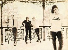 an old photo of four people standing in front of a gazebo with snow on the ground