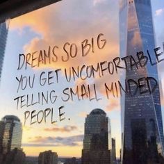 a window with writing on it in front of a cityscape that reads, dreams so big you get uncomfortableable telling small minds people