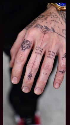 a person with tattoos on their fingers and hand