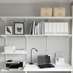 a laptop computer sitting on top of a white desk next to a bookshelf