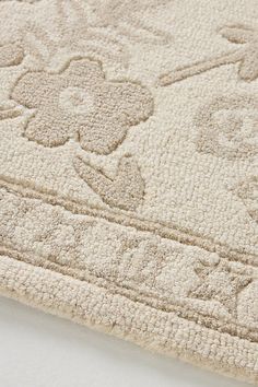 a close up view of a beige rug with flowers on the top and bottom corner