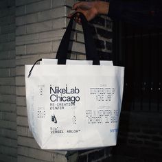 a white bag hanging from the side of a brick wall next to a person's hand