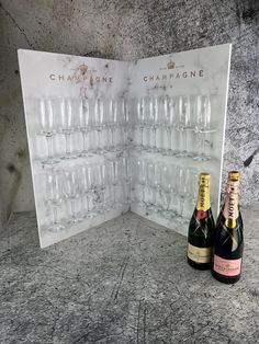 two bottles of champagne sitting next to each other in front of a wine glass display