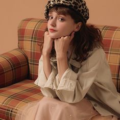 a woman sitting on top of a couch wearing a leopard print hat