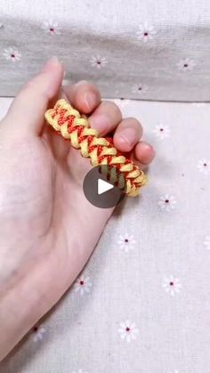 someone is holding a yellow and red braided bracelet