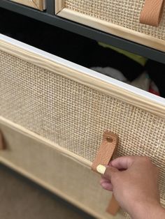 a person is holding a piece of wood in front of some drawers with wicker handles