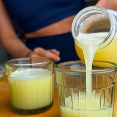 a person pouring milk into two glasses on a table