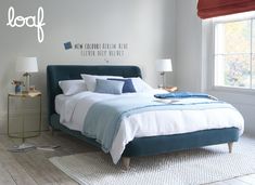 a bed with blue and white linens in a bedroom next to a lamp on a table