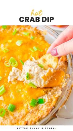 a hand dipping some food into a casserole dish with green onions and cheese