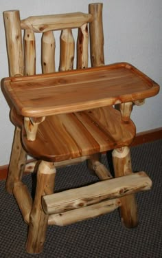 a wooden high chair sitting on top of a carpeted floor next to a wall