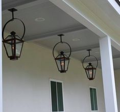 three hanging lanterns on the side of a house