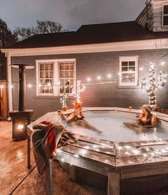 two women sitting in an outdoor hot tub with christmas lights on the side of it