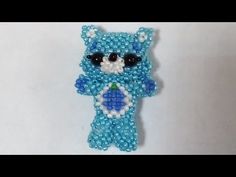 a blue beaded teddy bear with black eyes and an ornament in the shape of a cat