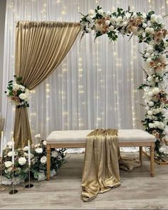 a white and gold wedding ceremony setup with flowers, greenery and draping