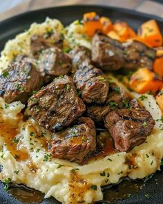 a black plate topped with mashed potatoes and meat