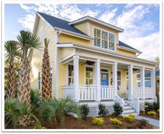 a yellow and white house with palm trees in front