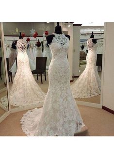 a white wedding dress on display in front of a mirror with other dresses behind it