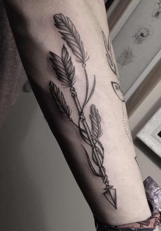 a person with a tattoo on their arm that has arrows and leaves coming out of it