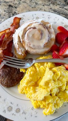 an english muffin, bacon, and scrambled eggs on a plate with a fork