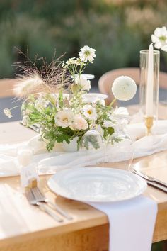 the table is set with white flowers and silverware