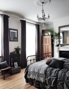 a bed sitting in a bedroom next to a window covered in black curtains and pillows