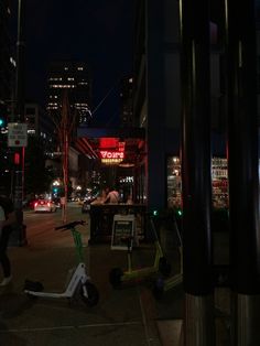 a city street at night with traffic lights and scooters