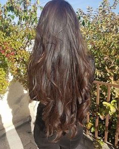 the back of a woman's head with long, dark brown hair and black pants